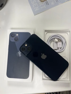 iPhone 13 - Snygg iPhone 13 i blått med originalkartong och laddkabel. Telefonen har dubbla kameror och platt design. Mindre repor syns på baksidan, men i övrigt gott skick. Perfekt för dig som vill ha en kraftfull och stilren smartphone.