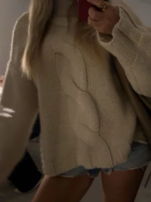 Populär stickad tröja med fläta från Zara - Supermysig beige stickad polotröja med oversized passform och stor fläta framtill. Tröjan har långa ärmar och ribbade muddar vid ärmslut och nederkant. Perfekt för lager-på-lager under kyliga dagar. Slutsåld på Zaras hemsida