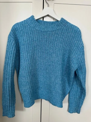 Blå stickad tröja XS - Blå stickad tröja i storlek XS. Tröjan har en grov ribbstickad struktur, rund hals och långa ärmar. Sparsamt använd!