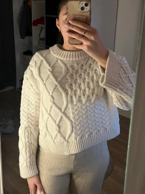 Vit stickad tröja med flätmönster - Säljer en supermysig vit stickad tröja från H&M med flätmönster framtill och på ärmarna. Väldigt tjockt, varmt och skönt material.