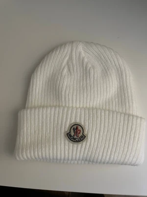 Moncler mössa - En vit Moncler mössa,perfekt nu under vintern. Fick den i present men har inte kommit till användning.