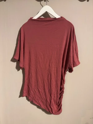 Rostrosa t-shirt från 157, storlek M - Säljer en rostrosa t-shirt från 157 i storlek M. T-shirten har korta ärmar och är gjord i mjuk bomull. Modellen är loose fit och har en enkel, clean look utan mönster eller tryck. Perfekt för dig som gillar basic och avslappnad stil.