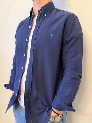 Mörkblå Ralph Lauren skjorta - En snygg polo skjorta som passar till alla tillställningar! Klassisk mörkblå som funkar till allt oavsett årstid eller tillfälle. Skjortan är i slim-fit modell.  Storlek👔: M Nypris💰: ca 1399 kr