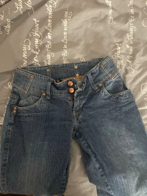 Blå Havana Denim jeans - Säljer ett par klassiska blå jeans från Havana Denim med skön passform. Jeansen har låg midjade, fem fickor och snygga kopparfärgade knappar. Materialet är slitstarkt jeans och de har kontrastsömmar för en extra detalj.