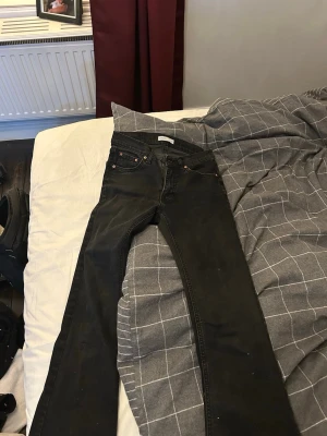 Svarta Perfect Jeans i storlek 36 - Säljer ett par svarta jeans från Gina Tricot i storlek 36. De har klassisk femficksdesign, utsvängda ben och snygga kopparfärgade nitar. Jeansen är i stretchigt material och har en stilren look som passar till det mesta.