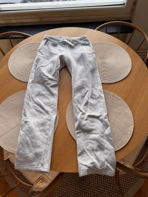 Ljusgrå mjukisbyxor med snörning - Säljer ett par ljusgrå mjukisbyxor med snörning i midjan. Byxorna har en rak passform och är tillverkade i mjukt bomullsmaterial, perfekta för chill dagar. Enkla och stilrena utan synliga loggor eller mönster.