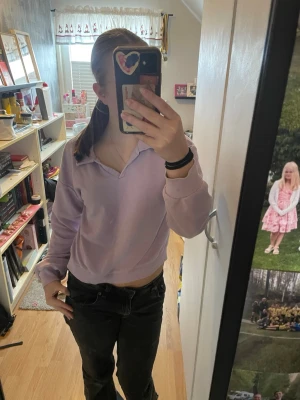 Ljuslila collartopp från XOXO Friends - En ljuslila topp med krage och v-ringning från XOXO Friends. Toppen har långa ärmar och är tillverkad i mjuk bomull. Perfekt för dig som gillar en chill och enkel stil med en twist av färg.