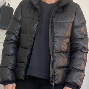 Svart puffer jacka  - Svart puffer jacka från H&M. Helt ny aldrig använd, bara provad.  Ganska stor i storleken strl 164 men på bilden är den en vuxen som har den på sig. Skulle säga att den motsvarar en liten xs. 