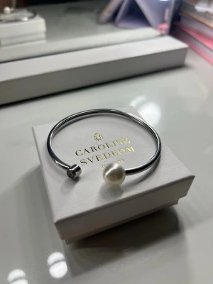 Snygg silverfärgad pärlarmband - Stilrent armband från Edblad ( inte Caroline svedbom❗️) i silverfärg med öppen design. Ena änden har en vit pärla och andra änden en klar sten. Armbandet är även justerbart så det passar perfekt till alla.💕
