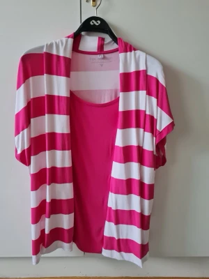 Randig topp från Bonprix strl 52/54 - Säljer en topp från Bonprix bpc collection i rosa och vitt med breda ränder. Toppen har korta ärmar och är tillverkad i mjuk viskosblandning med lite stretch. Storlek EUR 52/54. Kan hämtas i Vallentuna.