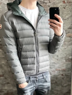 Grå Colmar pufferjacka med huva - Säljer en grå pufferjacka från Colmar med huva och dragkedja framtill. Jackan har quiltad design, två sidofickor med dragkedja. Märkena är lite slitna. 
