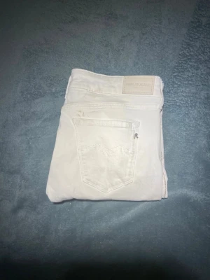 Vita Replay jeans slim fit w29 L30 - Snygga vita jeans från Replay med klassisk femficksdesign och slim fit-passning. Byxorna har en stilren look med diskret Replay-logga på bakfickan och är tillverkade i mjukt bomullsmaterial med lite stretch för extra komfort. Perfekta för dig som gillar en clean och fräsch stil.