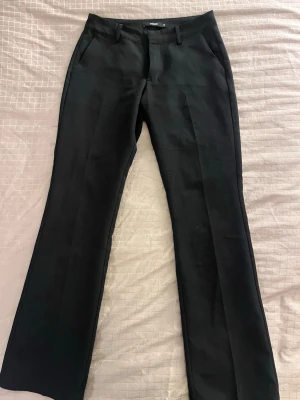 Svarta kostymbyxor  - Snygga svarta kostymbyxor från bikbok med raka ben och pressveck. Byxorna har låg midja. Perfekta till en clean och stilren look. 