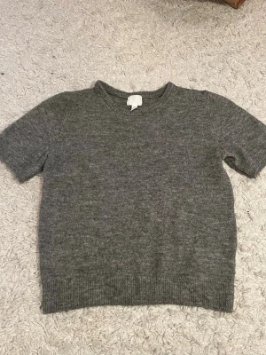 Grå stickad kortärmad tröja H&M - Mysig grå stickad tröja från H&M med korta ärmar och rund hals. Använd några fåtal gånger. Väldigt gosig och fin!!💞💞