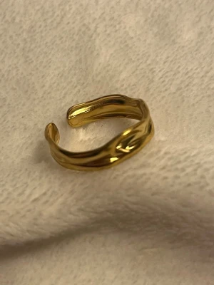 ✨Guldfärgad vågig ring✨ - Superfin guldring med mjuk, vågig design som ger ett modernt och stilrent uttryck ✨ Den öppna formen gör att ringen är justerbar och enkel att anpassa efter finger.  ✨ Trendig vågig form ✨ Justerbar storlek ✨ Lätt att matcha med andra ringar ✨ Passar både vardag och fest  I fint skick 🤍 Skickas snabbt 📦 Skriv om du vill ha fler bilder!