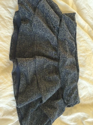 Glittrig mörkblå kortkjol - Snygg glittrig mörkblå kortkjol med stretchig midja. Kjolen har ett diskret glittrande tyg som ger en festlig känsla och sitter tajt mot kroppen. Perfekt för dig som vill sticka ut lite extra.