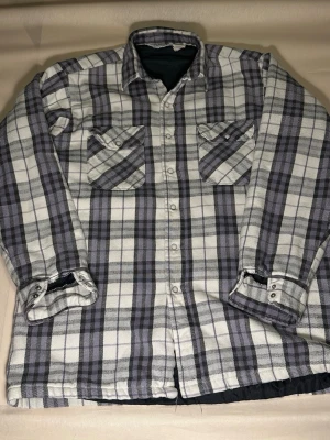 Vintage Quilted Flannel Shirt Jacket – Plaid – Made in USA - Brand: Five Brother Size: Large  (16–16½) Fit: Regular / Oversized L Material: Cotton flannel shell, quilted synthetic lining Style: Workwear / Lumberjack / Americana Era: Likely 90s Made in: USA Attention: This piece has lived. If flaws bother you, skip it Description: Heavy plaid flannel shirt jacket by Five Brother. Pearl Snap-button front and cuffs. Dual chest pockets with snap closure. Quilted insulated lining for warmth. visible wear consistent with age, including fraying in diamond stitch