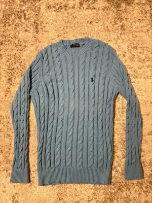 Blå kabelstickad tröja Polo Ralph Lauren - Snygg blå kabelstickad tröja från Polo Ralph Lauren. Perfekt för lager-på-lager och klassisk stil. Storleken är M hör av dig vid frågor 