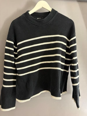 Svartvit randig stickad tröja Gina Tricot - Snygg svart stickad tröja från Gina Tricot med vita horisontella ränder. Tröjan har rund halsringning, långa ärmar och ribbade muddar. Perfekt för dig som gillar klassisk och avslappnad stil.