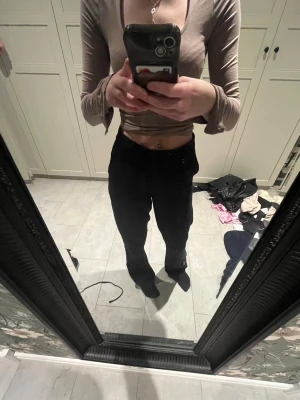 Svarta kostymbyxor med rak passform - Säljer ett par klassiska svarta kostymbyxor med rak passform och hög midja. Byxorna har en stilren look och passar perfekt till en snygg topp eller skjorta. Materialet känns mjukt och följsamt, vilket gör dem riktigt bekväma att bära.