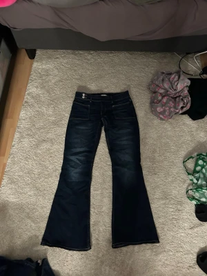 Mörkblå bootcut jeans Gina Tricot - Snygga mörkblå bootcut jeans från Gina Tricot. Jeansen har klassisk femficksdesign, markerade sömmar och utsvängda ben. Perfekta för dig som gillar en retroinspirerad look och vill ha ett par jeans som sticker ut lite extra.