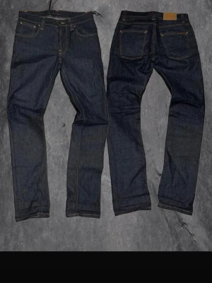 Nudie jeans - Snygga mörkblå jeans i klassisk rak modell med fem fickor och kontrastsömmar. Jeansen är tillverkade i kraftig denim och har en tidlös look som passar till det mesta. Perfekta för dig som gillar stilrena och enkla jeans.