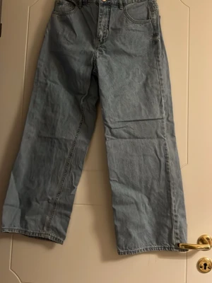 Ljusblå wide jeans från HM - Säljer ett par ljusblå jeans från HM med breda ben och klassisk femficksdesign. Jeansen har normal midja och är tillverkade i bomullsdenim. Perfekta för en avslappnad och trendig look. Midjan-39 cm, längd-94cm. Superfina i nyskick, bilder visar inte riktig blå färg, nytt skick.