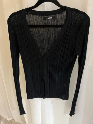 Svart ribbad kofta från Bik Bok - Svart ribbad kofta med djup V-ringning och lång ärm