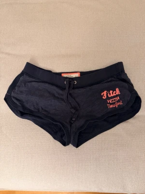 Mörkblå shorts från Abercrombie & fitch - Snygga lågmidjade mörkblå shorts från Abercrombie & fitch med rosa broderad logga och snörning i midjan. 