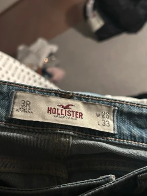 Ljusblå slitna jeans från Hollister - Ljusblå jeans från Hollister med flera slitningar och hål på benen. 