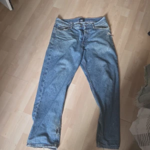 Blå jeans från Sweet SKTBS - Klassiska blå jeans från Sweet SKTBS med rak passform och slitna detaljer vid benslut och fickor. Jeansen har fem fickor, dragkedja och knapp i midjan. Perfekt för dig som gillar en avslappnad och streetig look. Ganska slitna och har några hål. Man kan pruta ner priset jag vill inte ha dem längre och vill testa att sälja istället för att slänga.