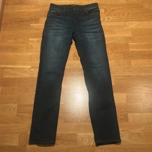 Mörkblå slim straight jeans 29/32 -  Mörkblå jeans med slim straight passform och  orangea sömmar. Byxorna har knäppning med knappar och innerfoder i fickan. Skick 8,5/10. Hör gärna av er!