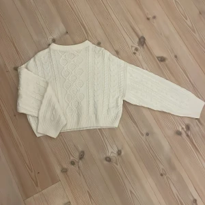Vit stickad tröja från Gina Tricot - Superfin vit stickad tröja från Gina Tricot med snyggt flätmönster och ribbade muddar. Tröjan är croppad och har lång ärm. Står ingen storlek i men passar mig som använder XS-S  