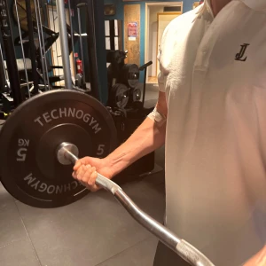 Vit pikétröja från Jepson Lorenz - Säljer en fräsch vit pikétröja från JL med klassisk krage och tre knappar framtill. Tröjan har korta ärmar och en stilren svart JL-logga broderad på bröstet. Tillverkad i mjuk bomull som känns skön mot huden. Ny släppt ifrån märket