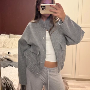 Grå oversized bomberjacka med fickor - Säljer en grå oversized bomberjacka med breda ärmar och stora fickor framtill. Storlek XS/S men har en lite ocersize fit. Från Nelly 2023, knappt använd. Nypris 799kr. 