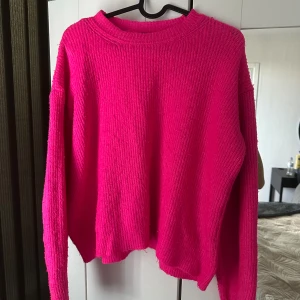 Chockrosa stickad tröja från Dilvin - Säljer en chockrosa stickad tröja från Dilvin med rund halsringning och lång ärm. Tröjan har en loose fit och är ribbstickad för en extra mysig känsla. Perfekt för dig som vill sticka ut med färg i garderoben!