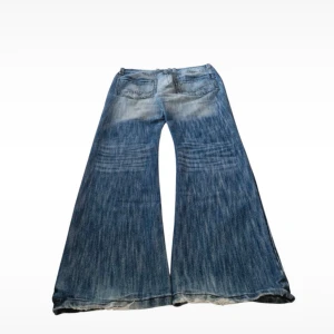 Blåa wide bootcut jeans - Säljer ett par blåa jeans med riktigt breda ben och bootcut-stil. Jeansen har slitningar och ljusa partier för en cool, vintage look. Klassiska bakfickor med kontrastsömmar och låg midja. Perfekta för dig som gillar statement-jeans med 00-talsvibbar. Har en fläck som syns på sista bilden. Midja: 42cm rakt över, totallängd: 111 cm, lår:29cm , 