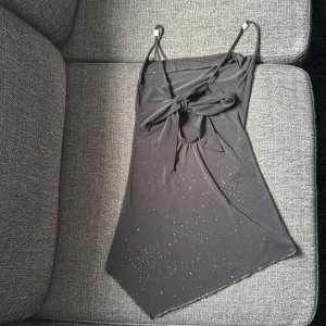 Svart glittrig linnetopp Sisters Point storlek xs/s - Svart linnetopp från Sisters Point med glittriga stenar och smala axelband med detaljer. Toppen har knyt bak, liten cut-out nederkant. (Toppen är sliten och väl använd, mycket glitter har åkt av)