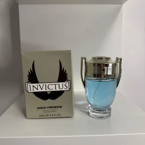 Paco Rabanne Invictus 100ml EdT - Fräsch och sportig parfym från Paco Rabanne, Invictus, i en cool troféformad flaska med silverdetaljer och ljusblått innehåll. Kommer i originalkartong med svart logga och vingar. Perfekt för dig som gillar maskulina och energiska dofter.
