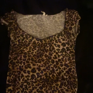 Leopardmönstrad topp från Nelly - Säljer en snygg leopardmönstrad topp från Nelly i storlek S. Toppen har korta ärmar, v-ringad hals och är i stretchigt, tunt material. Perfekt för dig som vill sticka ut med ett djurmönster och gillar trendiga detaljer.