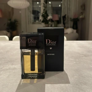 Dior Homme Intense Eau de Parfum - Dior Homme Intense är en lyxig herrparfym i en stilren, rektangulär glasflaska med svart lock och detaljer. Doften är varm och elegant, perfekt för dig som gillar exklusiva och maskulina toner. Flaskan har en transparent design som visar den gyllene vätskan inuti. Jag säljer denna på grund av att jag har tröttnat på den och kompisar har köpt samma. Kan nog vara 45 milliliter kvar i flaskan.