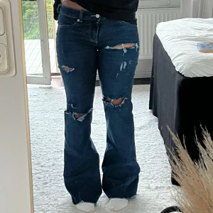 Mörkblå bootcut jeans med slitningar - Snygga lågmidjade mörkblå jeans med bootcut-modell o slitningar. 