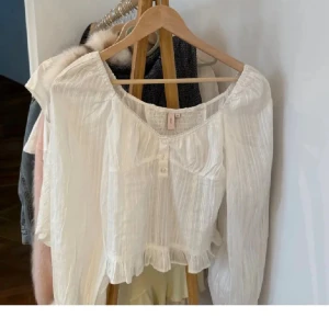 Vit blus med volang från Nelly - Supersöt vit blus från Nelly med v-ringad hals, knappar framtill och volangkant. Använt kanske två gånger!