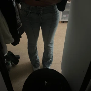 Lågmidjade  jeans från Bershka - Säljer ett par lågmidjade ljusblå jeans från Bershka i storlek 38. Jeansen har raka ben, dubbla knappar i midjan och markerade sömmar framtill. Klassisk femficksmodell i mjukt denimtyg som ger en snygg och avslappnad look.