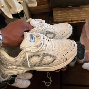 Dior B30 43/44 - Dior B30 skor vita med silvrig logga. Skick 8/10 Ny pris 6999 :-   Mitt pris 2599 :- Hör av er vid minsta lilla bekymmer 🙌
