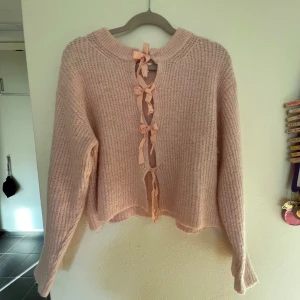 Rosa stickad kofta med rosetter Gina Tricot - Supersöt ljusrosa stickad kofta från Gina Tricot med långa ärmar och fina rosett-detaljer framtill. Koftan har en mysig, lite loose passform och är perfekt för lager-på-lager. Snygg till både jeans och kjol!