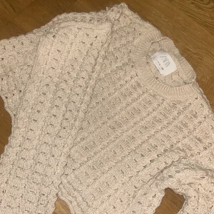 Beige stickad tröja från ZARA - Säljer en beige stickad tröja från ZARA med grovt hålmönster och rund hals. Tröjan har långärmade ärmar och en loose passform som ger en chill vibe. Perfekt för lager-på-lager och att styla med jeans eller kjol.