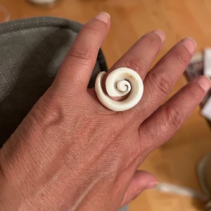 Vit Spiral snäckskalring  - Säljer en unik ring i spiralform. Ringen har en cool och konstnärlig design som verkligen sticker ut. Perfekt accessoar för dig som gillar att uttrycka din stil med smycken som syns.