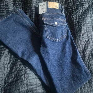 Blå bootcut jeans från 157 - Snygga blå bootcut jeans från 157 i storlek XXS. De har en låg midja och klassisk femficksdesign. Perfekta för en avslappnad stil med en touch av 90-tal.Helt nya med prislapp kvar