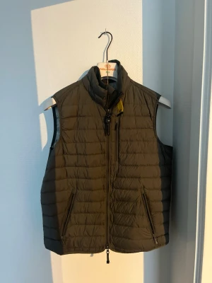 Mörkgrön dunväst från Parajumpers - Snygg mörkgrön dunväst från Parajumpers i storlek M. Västen har quiltad design, hög krage och dragkedja framtill samt två praktiska fickor med dragkedja. Perfekt för lager-på-lager. Köpt från johnells hemsida. Knappt andvänd!!